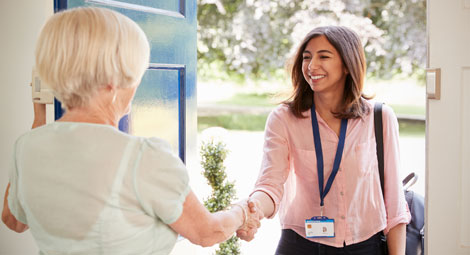 An older female shaking hands with a female doctor in her home